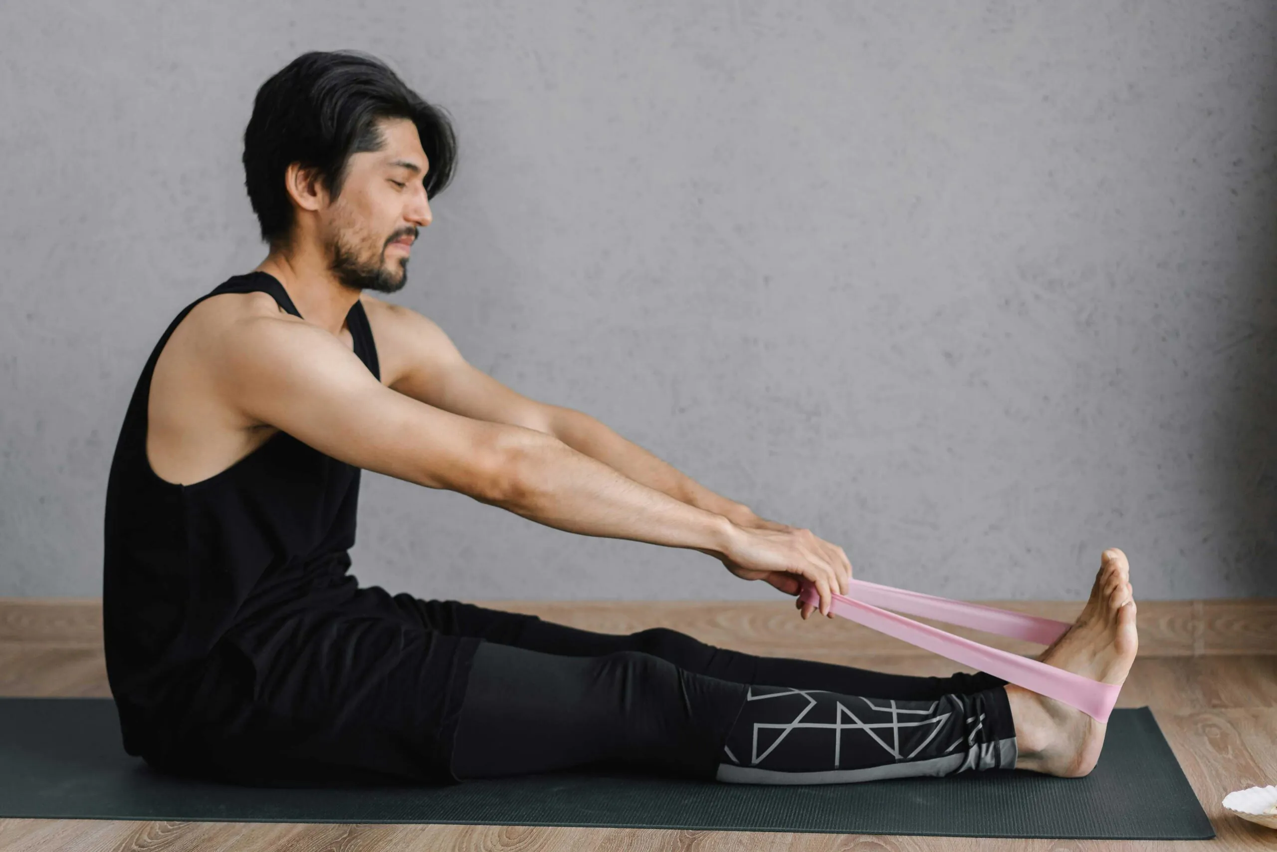 a young man using a rubber band to help stretch his knees