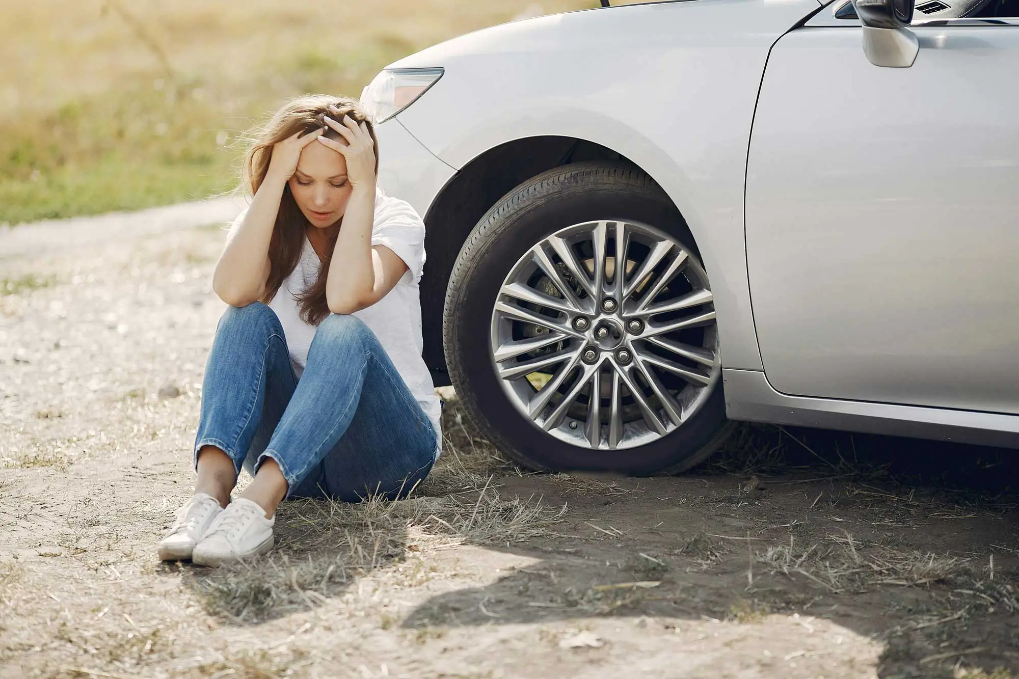 a woman sitting next to her car in pain from an accident